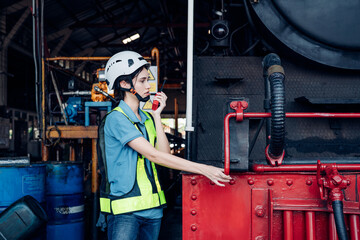 Portrait of professional woman engineer in white hardhat standing and working in train factory.