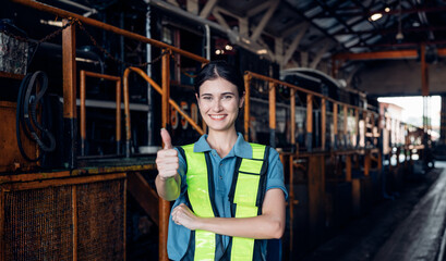 Portrait of professional woman engineer in white hardhat standing and working in train factory.