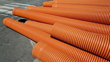 Corrugated sewer pipe, double-layer. Pipes stacked together, repair work in the city. Orange sewer pipes, close-up. Pipes are able to withstand variable loads from the soil
