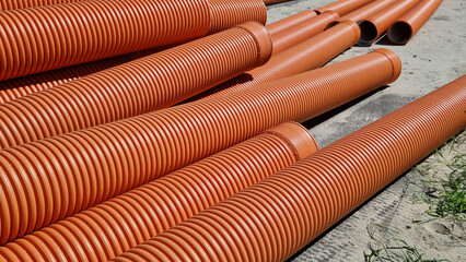 Corrugated sewer pipe, double-layer. Pipes stacked together, repair work in the city. Orange sewer pipes, close-up. Pipes are able to withstand variable loads from the soil