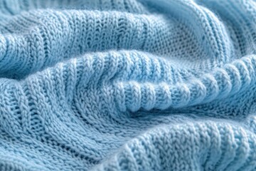 Close-up of soft, light blue knitted fabric with visible ribbed and cable stitch texture creating gentle waves and folds
