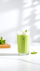 Fototapeta premium Refreshing Iced Matcha Latte with Mint Garnish on White Surface.