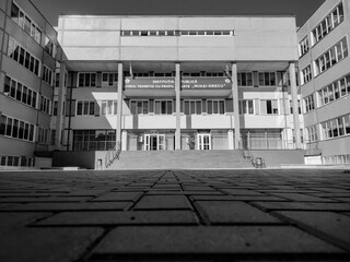 Monochrome low-angle view of the "Mihai Grecu" Arts School facade in Chisinau, with its symmetrical architecture and a paved courtyard