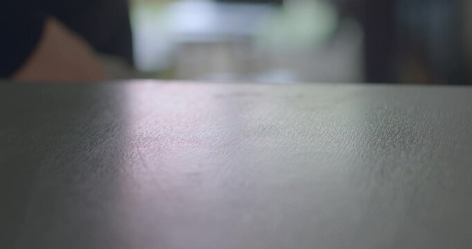 A closeup shot of a hand actively gesturing or moving gracefully over the surface of a table, effectively demonstrating interaction with the surrounding environment in a detailed way