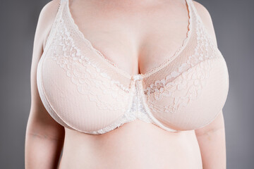 Large saggy breasts in a push-up bra, breastfeeding underwear, gray background