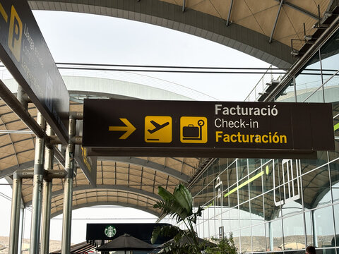 Alicante, Spain - August 26, 2025: Airport check-in sign with directional arrow and icons for flight and luggage, showcasing travel logistics and modern architecture