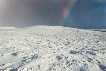 Snow covered mountain with a vivid rainbow: Slievenanee Mountain in County Antrim