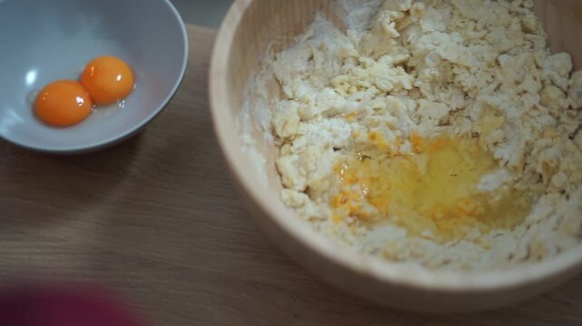 Carefully Mixing Together Dough with Egg in a Wooden Bowl for Baking ather and daughter cook together family quality time help cozy atmosphere authentic