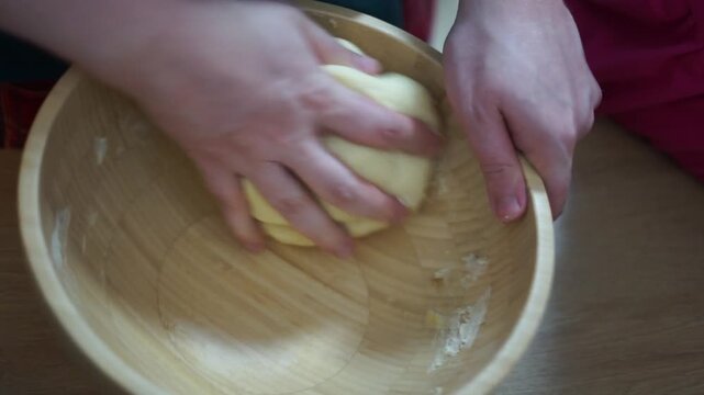 Hands are skillfully kneading dough inside a rustic wooden bowl ather and daughter cook together family quality time help cozy atmosphere authentic