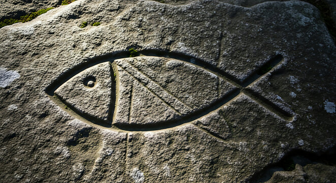Christian ichthys fish symbol carved in stone ancient religious sign jesus christ faith hope love belief ichtus