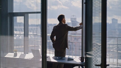 Corporate leader watching skyline reflecting ambitions. Thoughtful sad worker