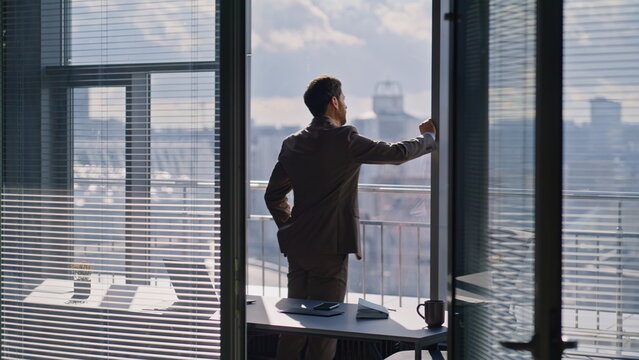 Corporate leader watching skyline reflecting ambitions. Thoughtful sad worker