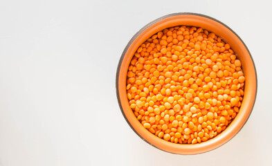 7Red lentils in a round ceramic plate. Healthy lifestyle. White background. Top view. Place for text.