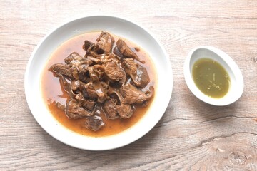 slice braised pork stew in herb brown soup dipping chili and sour sauce on plate