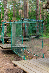 This tree climbing park features various obstacle courses and suspended walkways constructed from ropes and wood, nestled among tall trees, inviting young adventurers to enjoy nature