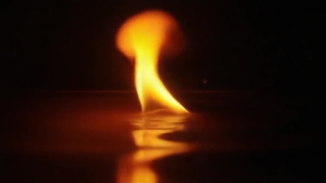 A fire is reflected in the water on a black background