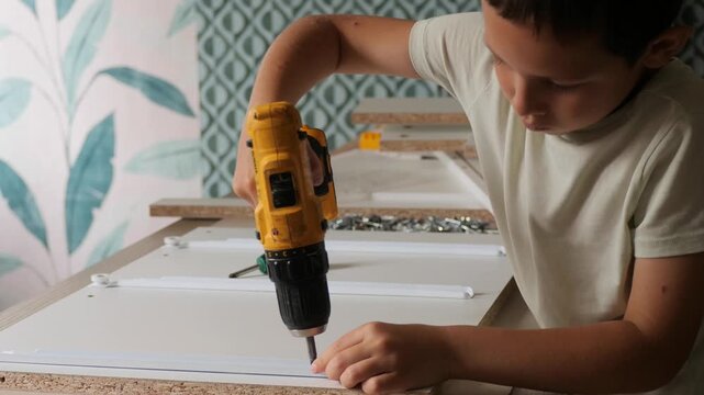 Boy using an electric drill - Child building furniture with tools - A child learns to use power tools safely, helping to build something for the home