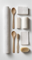 A top-down view of various natural, neutral-toned household items.  Wooden spoons, a roll of paper towels, and rectangular bars of soap.  Natural fiber cleaning tools