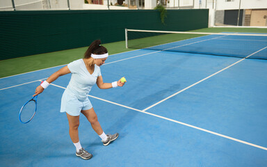 Female Tennis Player Preparing for Serve on Outdoor Blue Court