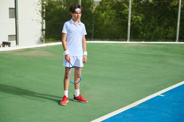 Obraz premium Young Player in Action on Outdoor Tennis Court with Racket in Hand