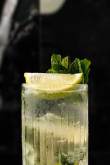 efreshing cocktail served in a tall glass with ice, lime wedges, and fresh mint leaves on a marble table. Perfect summer drink for bar, restaurant, or party concept © Влад Пентюк