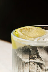 Refreshing cocktail served in a glass with ice cubes and lime slices. Close-up of a cold drink with condensation on the glass, perfect for summer, party, or bar concept. Crystal-clear beverage with ci