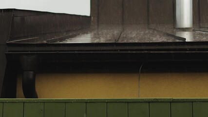 Rain falling on a sloping metal roof eloquently conveys the carefree atmosphere of a rainy day. Rain in the city, weather forecast, cloudy sky - Powered by Adobe