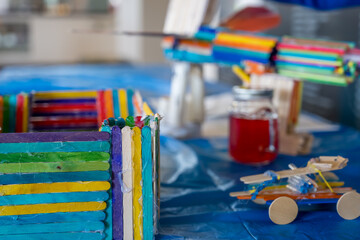Crafting colorful toys and structures using popsicle sticks and other materials in a bright indoor space
