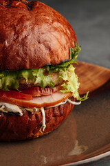 uicy gourmet burger with a fresh tomato slice on top of the bun. Delicious beef patty, melted cheese, lettuce, and vegetables served in a rustic bread bun. Appetizing fast food meal, perfect for lunch