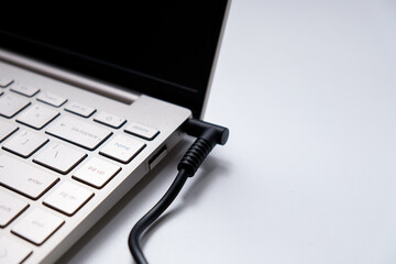 Charging laptop with power adapter isolated on white background
