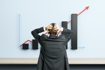Businessman holding head in front of rising bar chart and red arrow on wall symbolizing financial growth and leadership stress in modern office room.