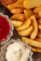 Crispy fried potatoes served with a variety of sauces. Golden French fries on a plate with ketchup, mayonnaise, and cheese dip. Close-up of tasty fast food snack, perfect for lunch, dinner, or party a