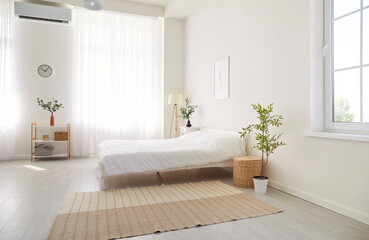 Empty bedroom with a cozy white bed in a home on a quiet morning. The comfortable and peaceful interior showcases a calm space, highlighting the simplicity and warmth of the house decor.