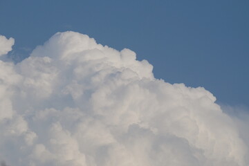 Fluffy white clouds billowing against a clear blue sky, creating a serene and tranquil atmosphere, perfect for nature-themed projects and backgrounds with copy space