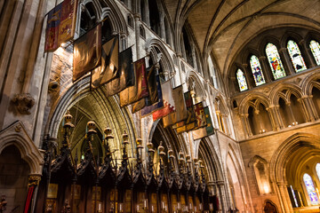 Interior of St Patricks Cathedral in Dublin Ireland with vaulted ceilings and colorful flags decorating the historic church