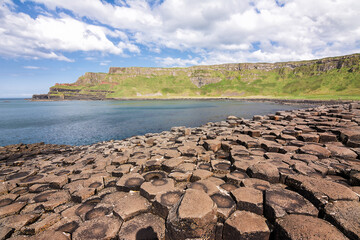 Hexagonal basalt columns at Giants Causeway Northern Ireland with sunburst sky evoking the legend of a giants causeway between Ireland and Scotland
