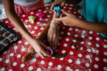 Children making cookies with cutters on red polka dot tablecloth