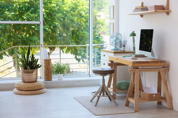 Home workspace. Modern computer and stationery on wooden desk near window indoors