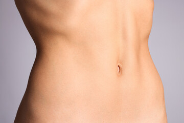 Woman with flat belly on grey background, closeup