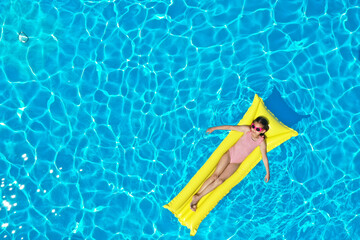 Girl on inflatable mattress in swimming pool, top view. Summer vacation