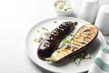 Slices of grilled eggplant with green onion and blue cheese on white table, closeup. Space for text