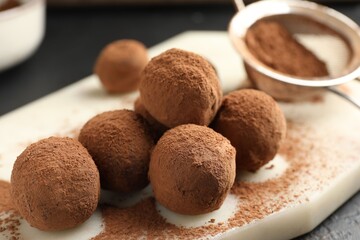 Tasty chocolate candies with cocoa powder on table, closeup
