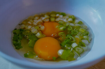 Cooking preparation, Process making an omelette. Mix two raw eggs with the leeks in a bowl. Breakfast menu. Copy space for text. Close up.