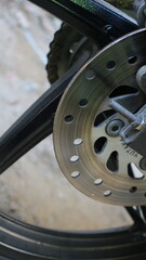 Closeup of a motorcycle rear disc brake system with visible rotor, caliper mount, and axle hardware, highlighting precision engineering and clean mechanical detail
