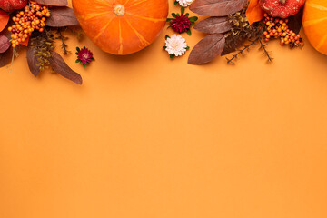 Cozy autumn flat lay composition with woolen scarf, cup of herbal tea and bright decorations on light terracotta background with copy space for your design.