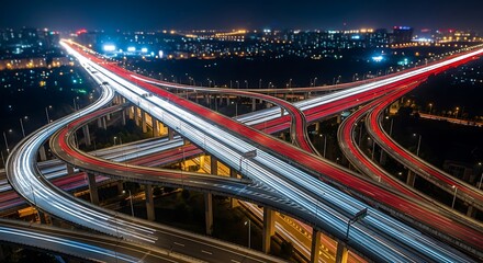 Aerial view of a complex highway interchange at night with light trails from cars