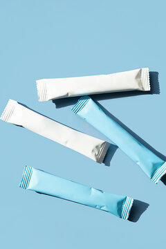 White and blue sachets of collagen supplement. Beauty and health product on blue background with copy space.