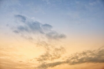 Stunning sunset sky featuring a beautiful gradient of soft blue and warm orange hues with delicate, wispy clouds. Ideal for backgrounds, nature, and dreamy concepts.