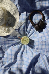 Picnic. Healthy matcha tea in a transparent glass stands on a blanket, and next to it are a hat, books and headphones