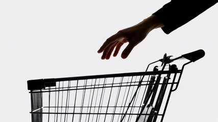 Hand reaching for empty black wire shopping cart on plain background